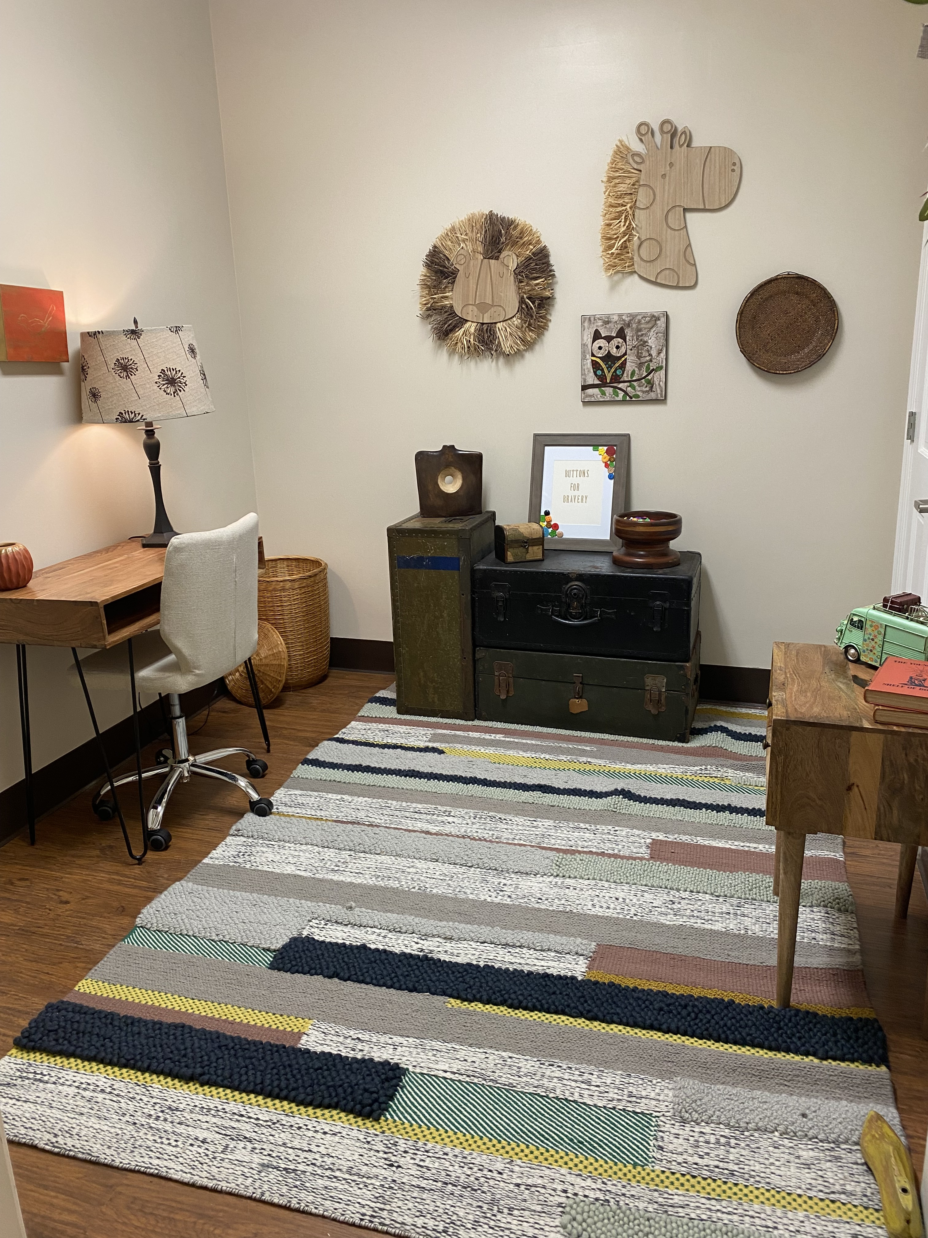 An office at the Center with a desk, colorful rug, and decorative trunks with Buttons for Bravery to give to children on top